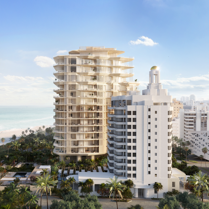 Beachfront view of a luxurious, modern high-rise, next to a historic white building.