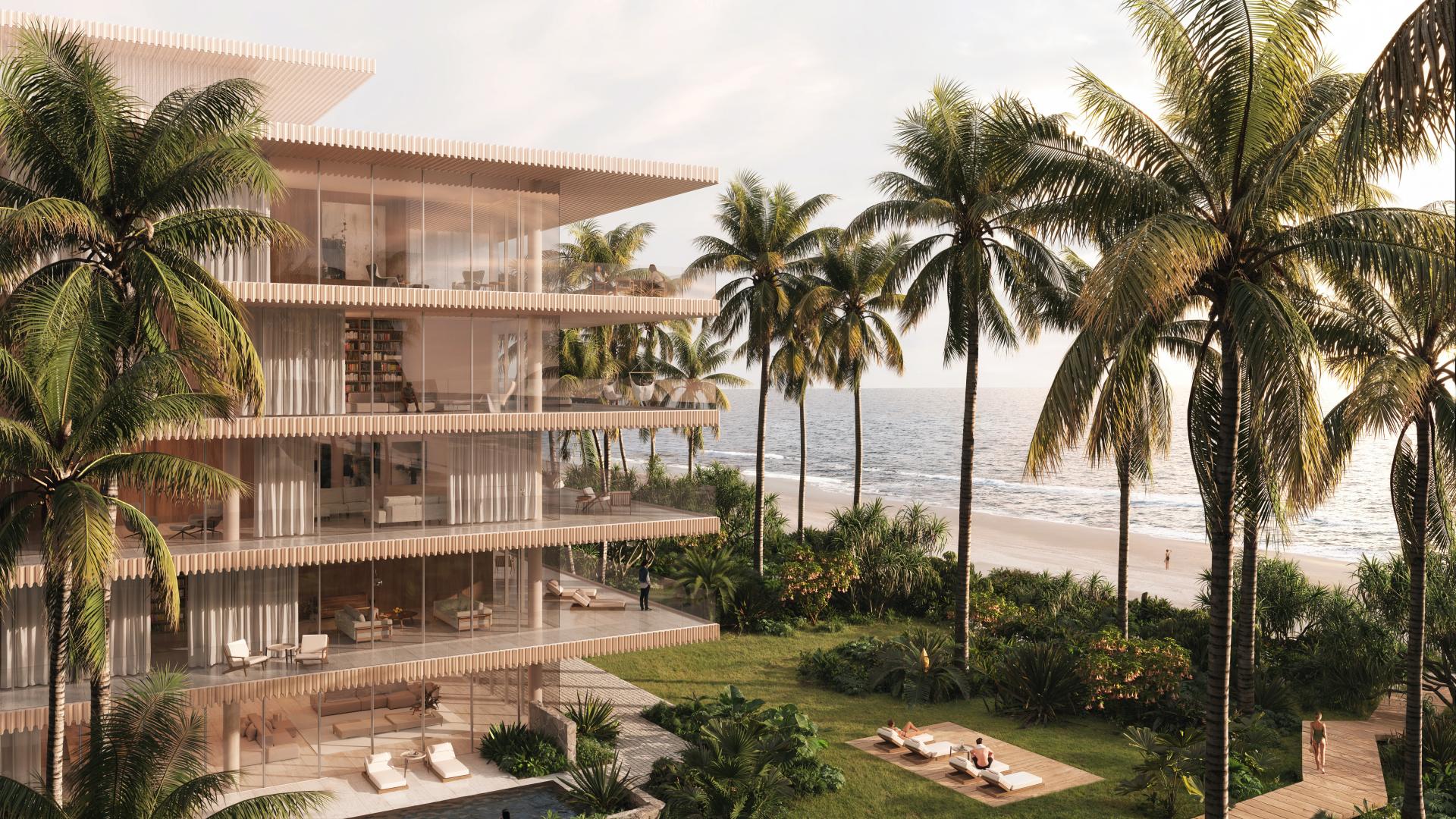 Beachfront residence with glass balconies, surrounded by palm trees, overlooking the ocean.