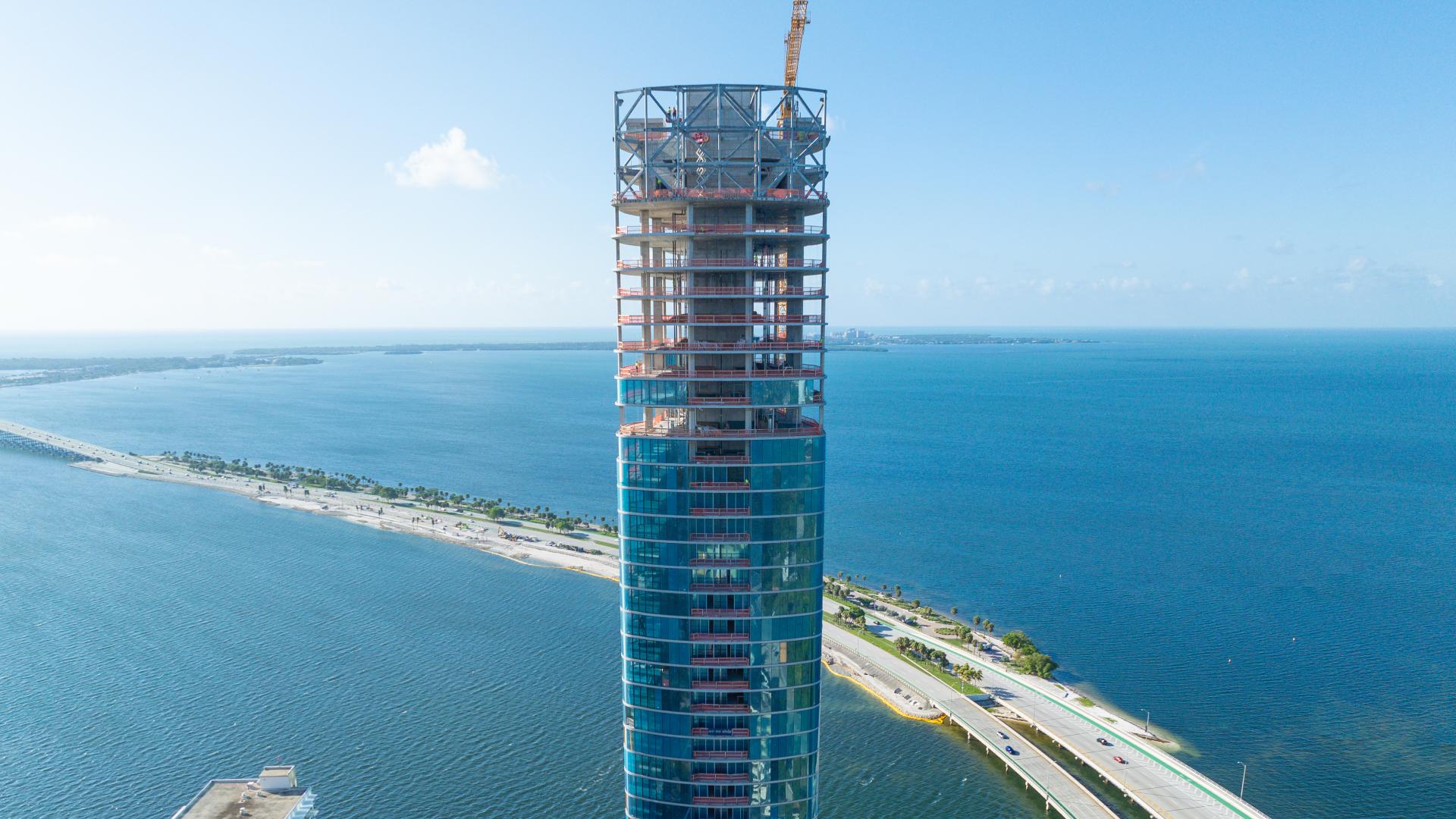 High-rise tower under construction by the waterfront.