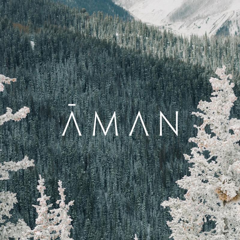 Snow-covered trees and dense forest with the text "AMAN" overlaid.