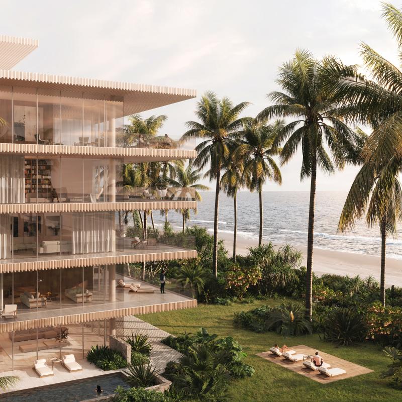 Beachfront residence with glass balconies, surrounded by palm trees, overlooking the ocean.